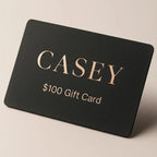 Black gift card with 'CASEY' and '$100 Gift Card' text on a beige background